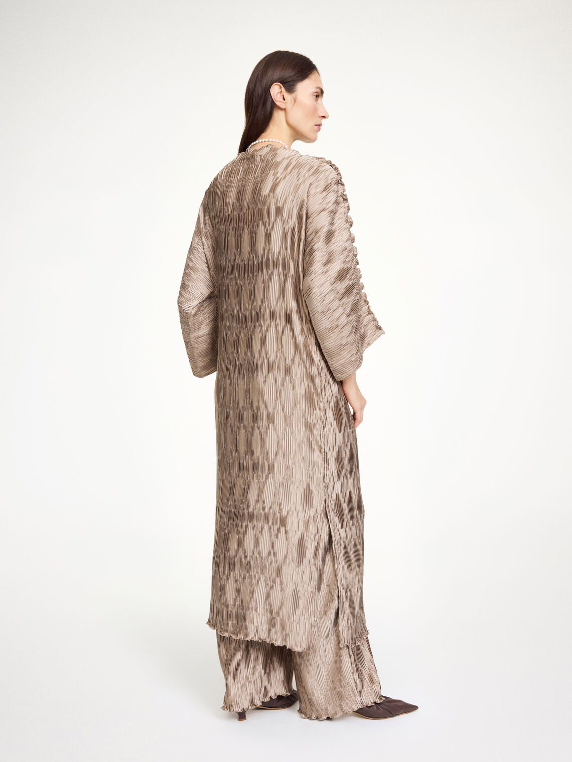 By Malene Birger Tralaido kjole i beige, med plissé struktur, båtutringning og vide ermer, laget av resirkulert polyester.