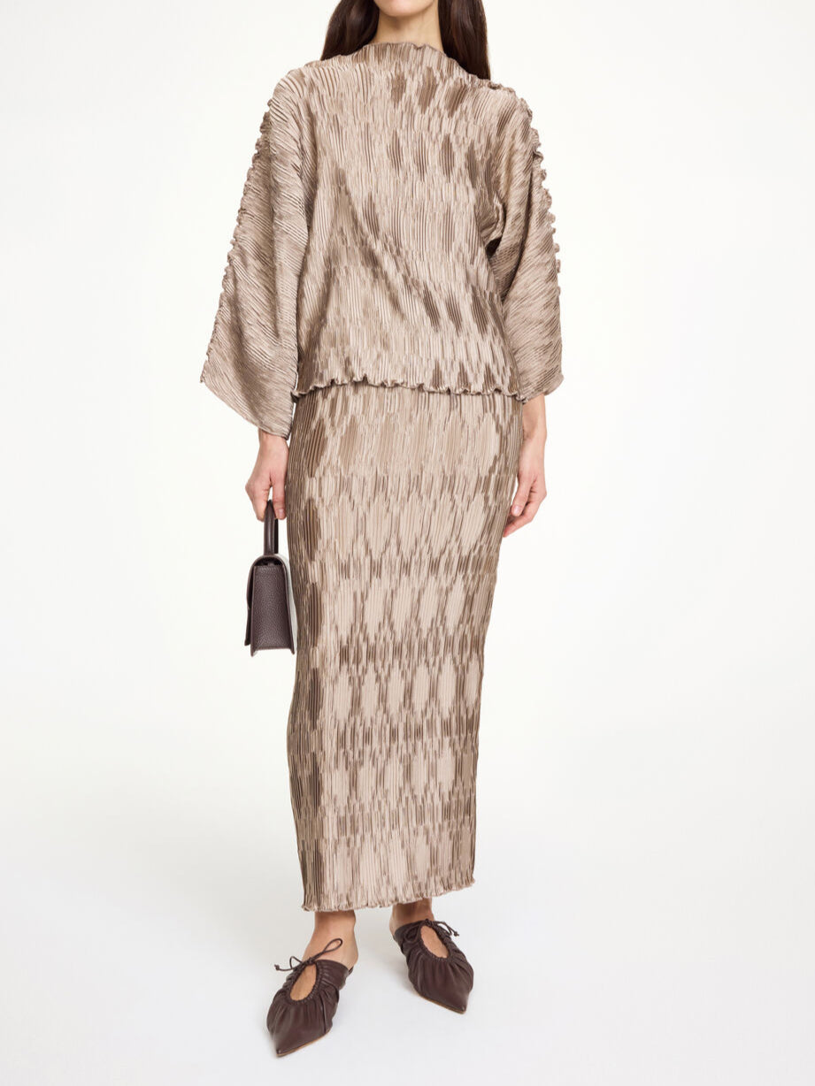 By Malene Birger Tralluman bluse i beige, laget av 100% resirkulert polyester, med plissé struktur, båtutringning og vide ermer.