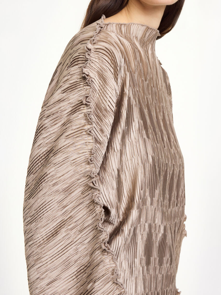 By Malene Birger Tralluman bluse i beige, laget av 100% resirkulert polyester, med plissé struktur, båtutringning og vide ermer.