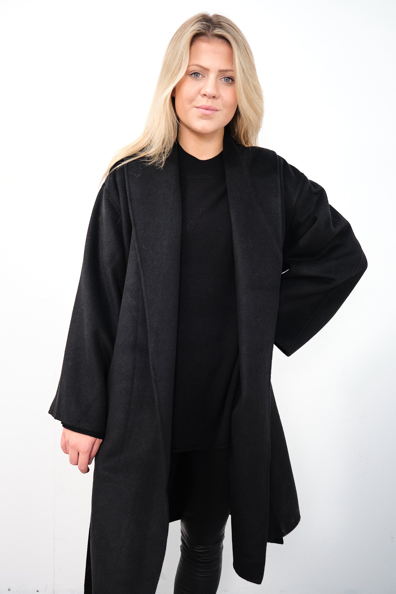 By Malene Birger Trullas kåpe i sort, med en sjal-lignende krage og en rett passform, laget av 100% ull.