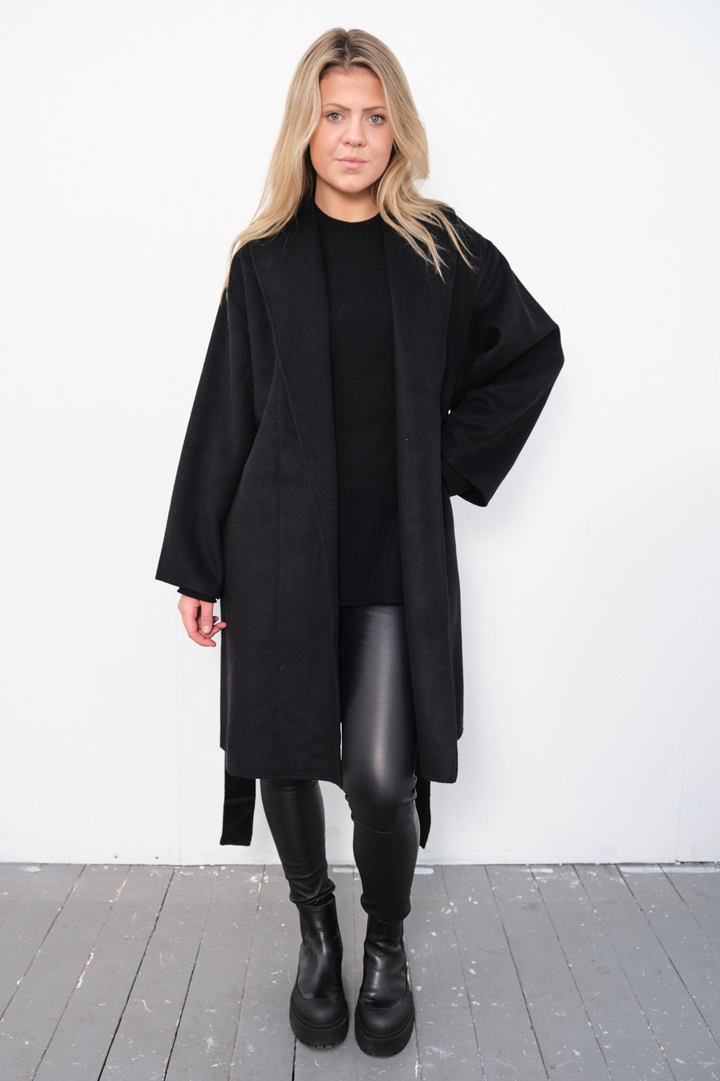 By Malene Birger Trullas kåpe i sort, med en sjal-lignende krage og en rett passform, laget av 100% ull.