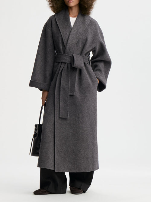 TRULLEM kåpe fra By Malene Birger i fargen mørkegrå, laget i 100% ull. Rett modell med sjal-liknende krage, lommer i siden og avtagbart belte.