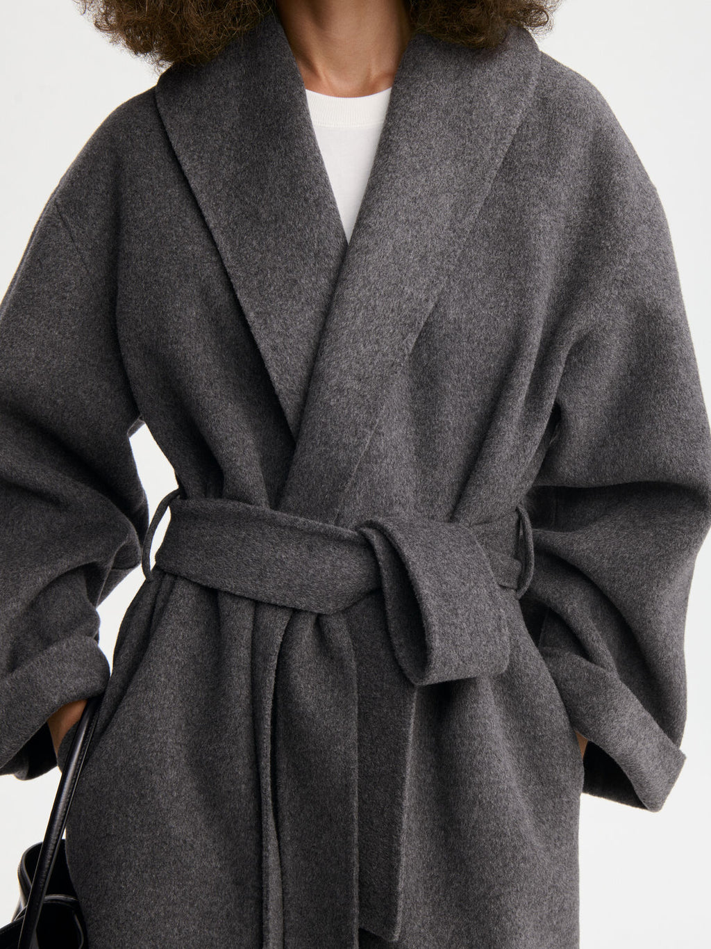 TRULLEM kåpe fra By Malene Birger i fargen mørkegrå, laget i 100% ull. Rett modell med sjal-liknende krage, lommer i siden og avtagbart belte.