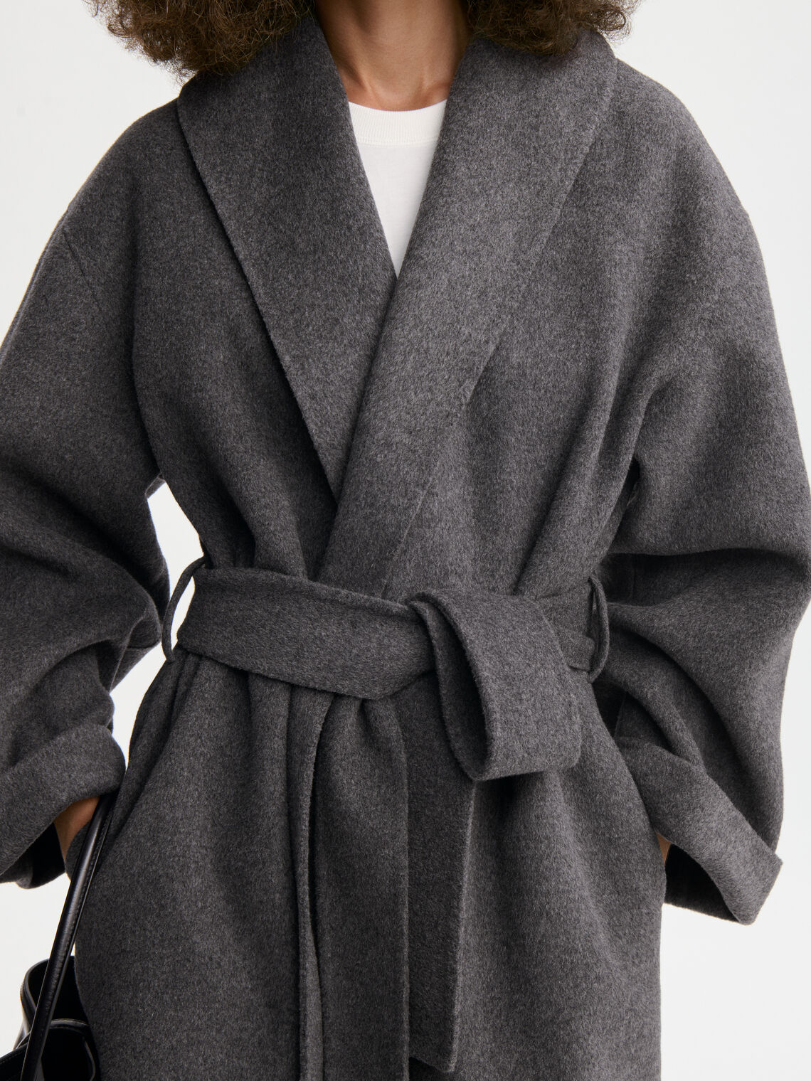 TRULLEM kåpe fra By Malene Birger i fargen mørkegrå, laget i 100% ull. Rett modell med sjal-liknende krage, lommer i siden og avtagbart belte.