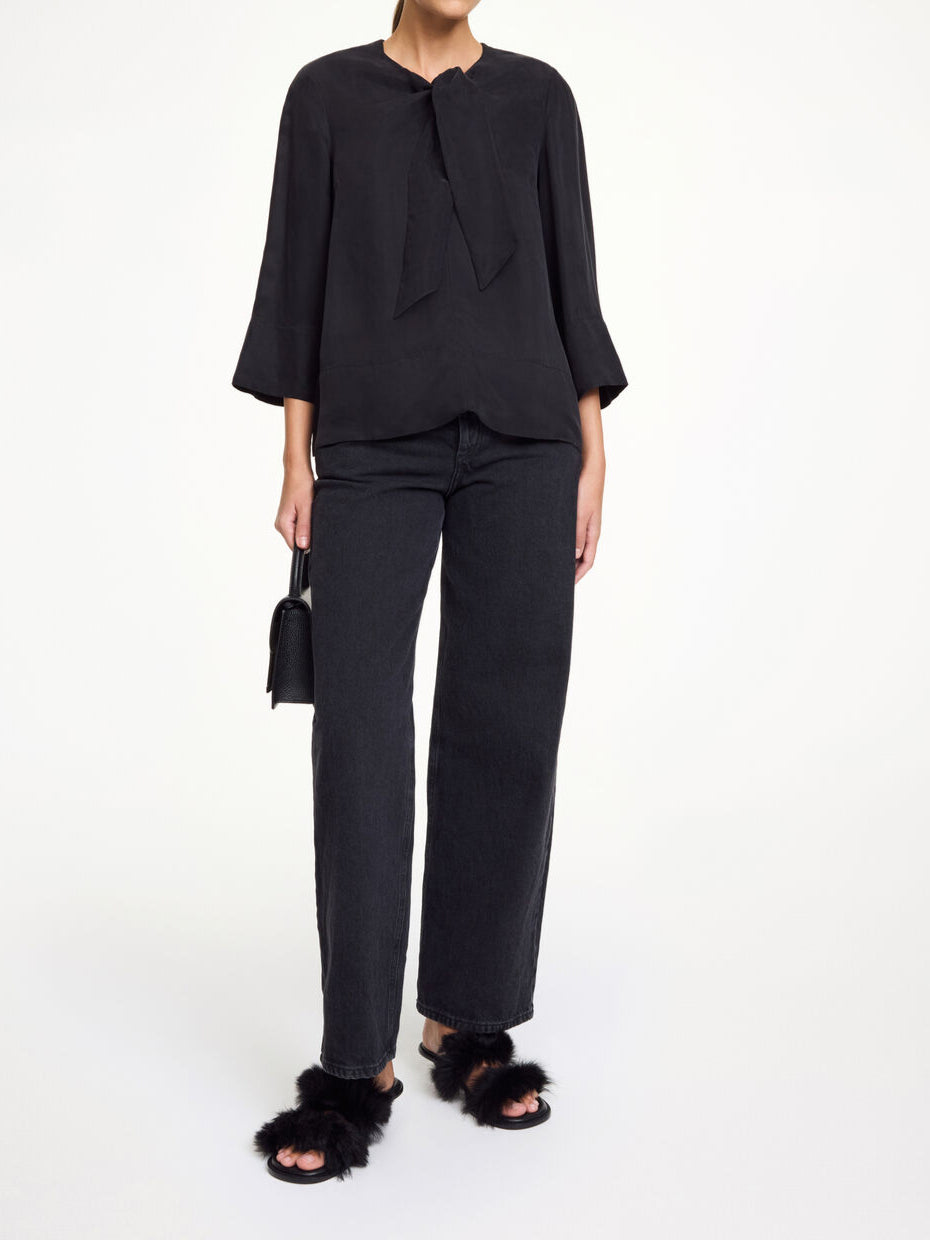 By Malene Birger Vega bluse i sort, med knyting i halsen, en løs passform og laget av en blanding av cupro og viskose.