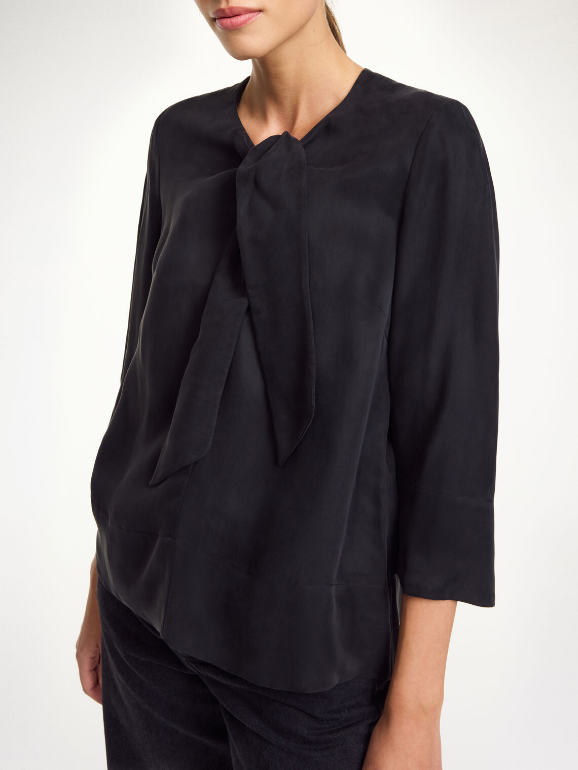 By Malene Birger Vega bluse i sort, med knyting i halsen, en løs passform og laget av en blanding av cupro og viskose.