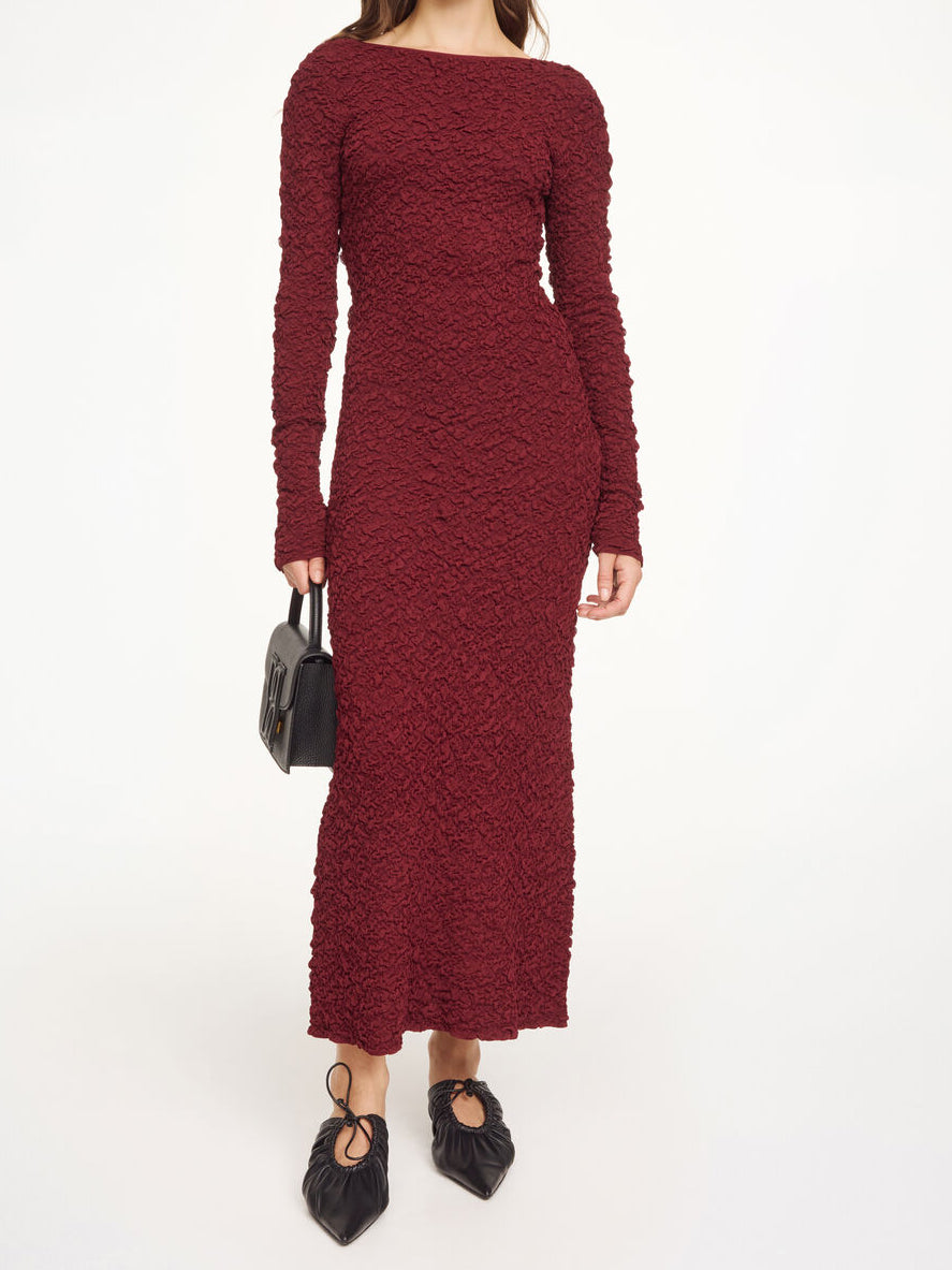 By Malene Birger Venus lang kjole i burgunder viskose med rund hals, v-rygg, lange ermer og smal passform.