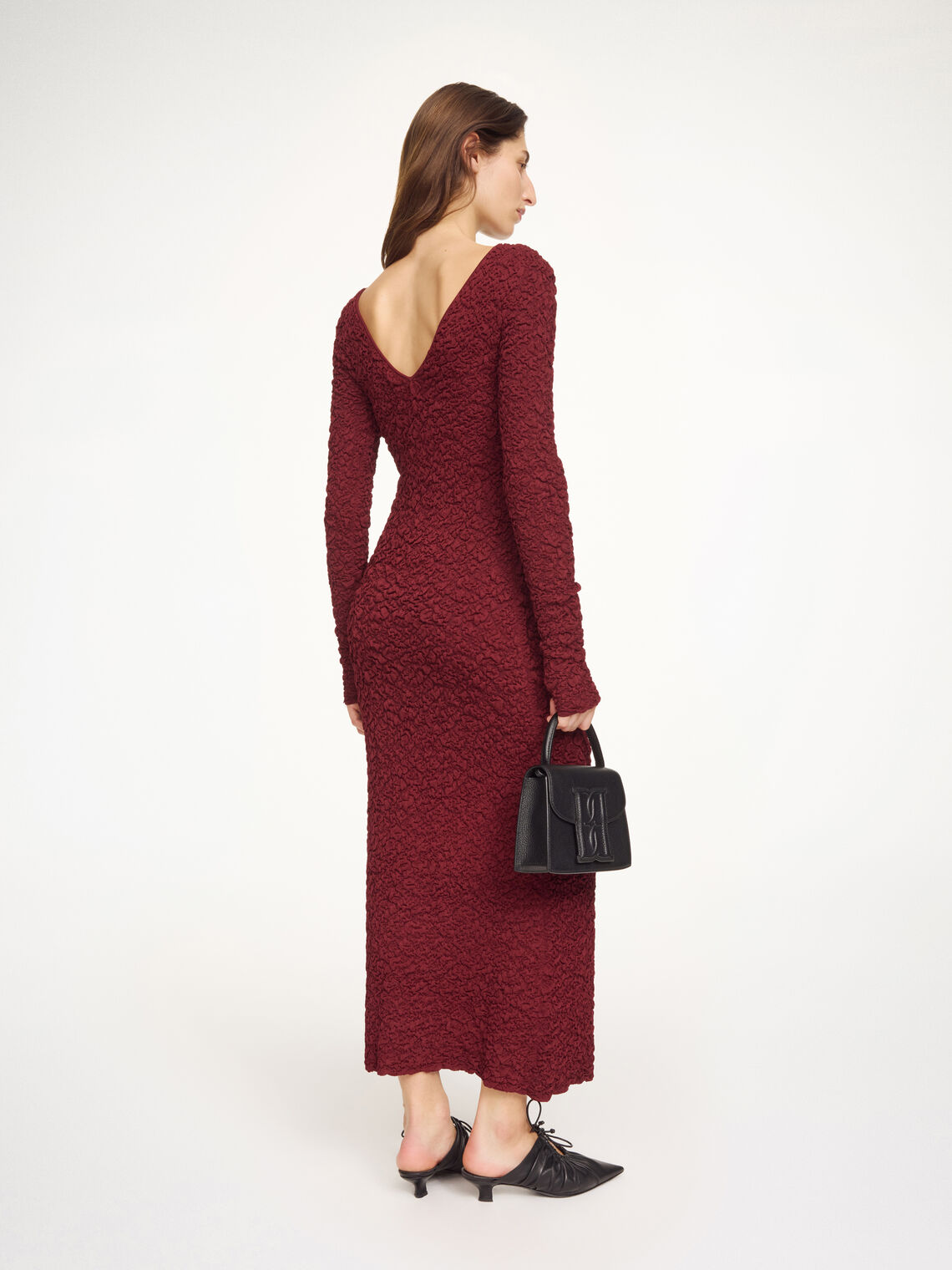 By Malene Birger Venus lang kjole i burgunder viskose med rund hals, v-rygg, lange ermer og smal passform.
