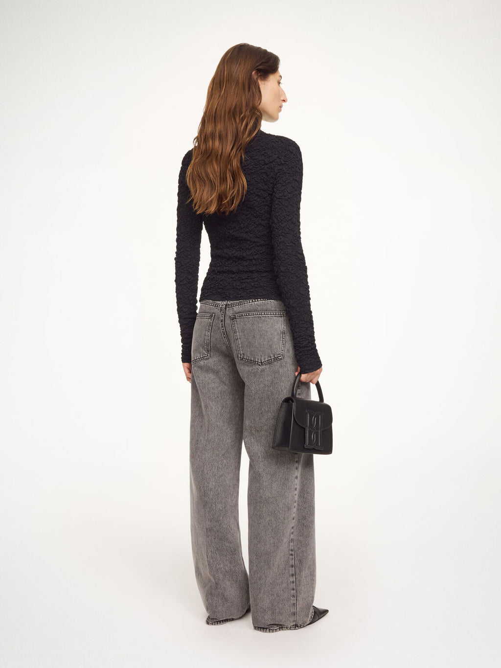 Aura-genser i fargen svart fra By Malene Birger med en stilfull struktur og elegant høy hals. Genseren har en smal passform som sitter tett etter kroppen, er laget i en noe gjennomsiktig og stretchy Lenzing Ecovero-viskose og har lange ermer som gir et dresset uttrykk.