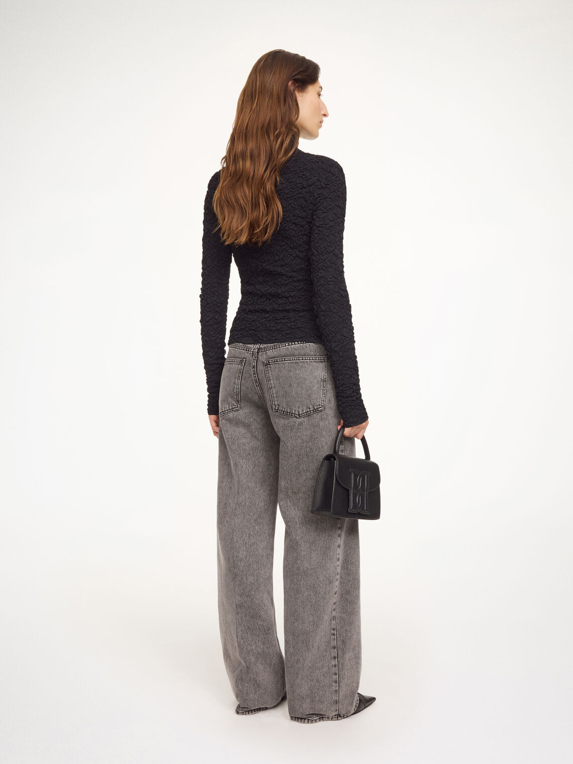 Aura-genser i fargen svart fra By Malene Birger med en stilfull struktur og elegant høy hals. Genseren har en smal passform som sitter tett etter kroppen, er laget i en noe gjennomsiktig og stretchy Lenzing Ecovero-viskose og har lange ermer som gir et dresset uttrykk.