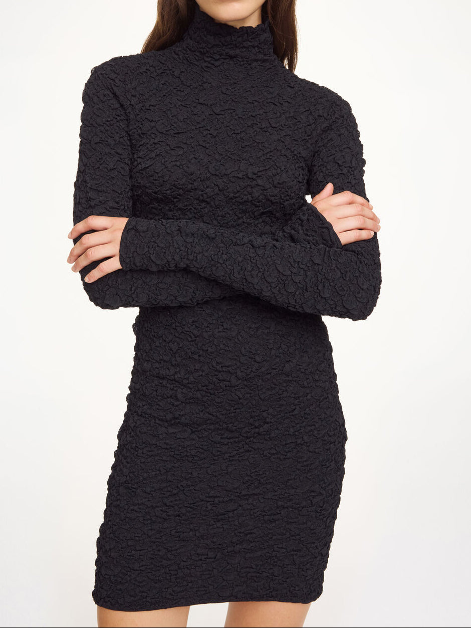 By Malene Birger Aurora kjole i sort viskose med hoyal hals, lange ermer og smal passform med strukturert stoff.