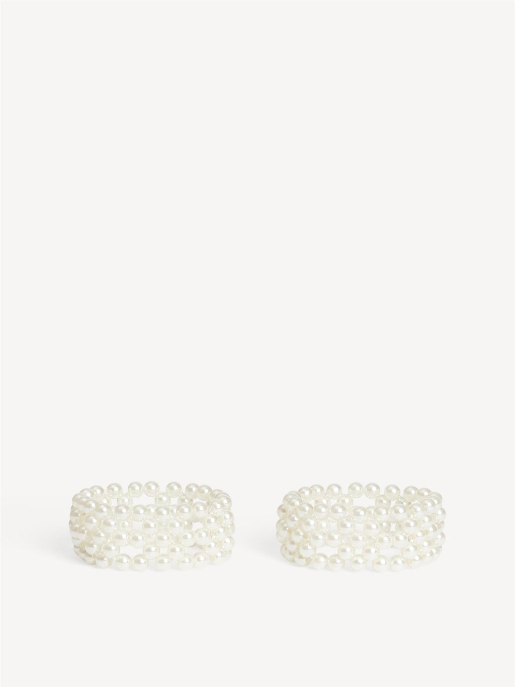 CHAKIE armbånd fra By Malene Birger i hvit. Laget i plastikk med falske perler og elastisk strikk. Feminine armbånd i onesize, selges i par.