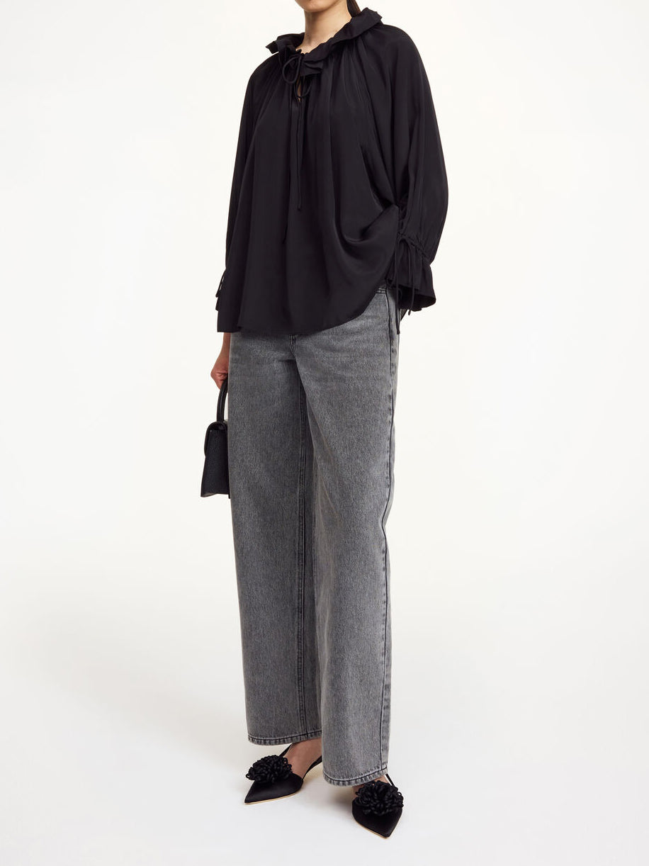 Sort DICTE bluse fra By Malene Birger i viskose og silke, oversized passform med v-hals, knyting og rysjedetaljer.