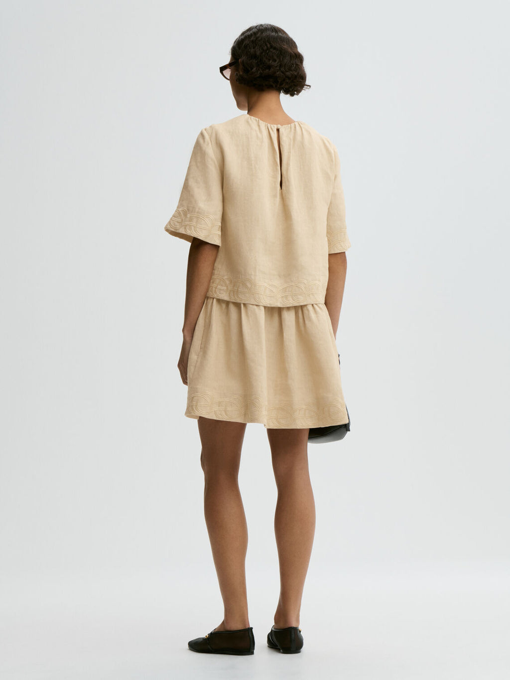 By Malene Birger Jania kjole i beige 100% lin med rund hals, knapplukking i nakken og swirl-broderi.