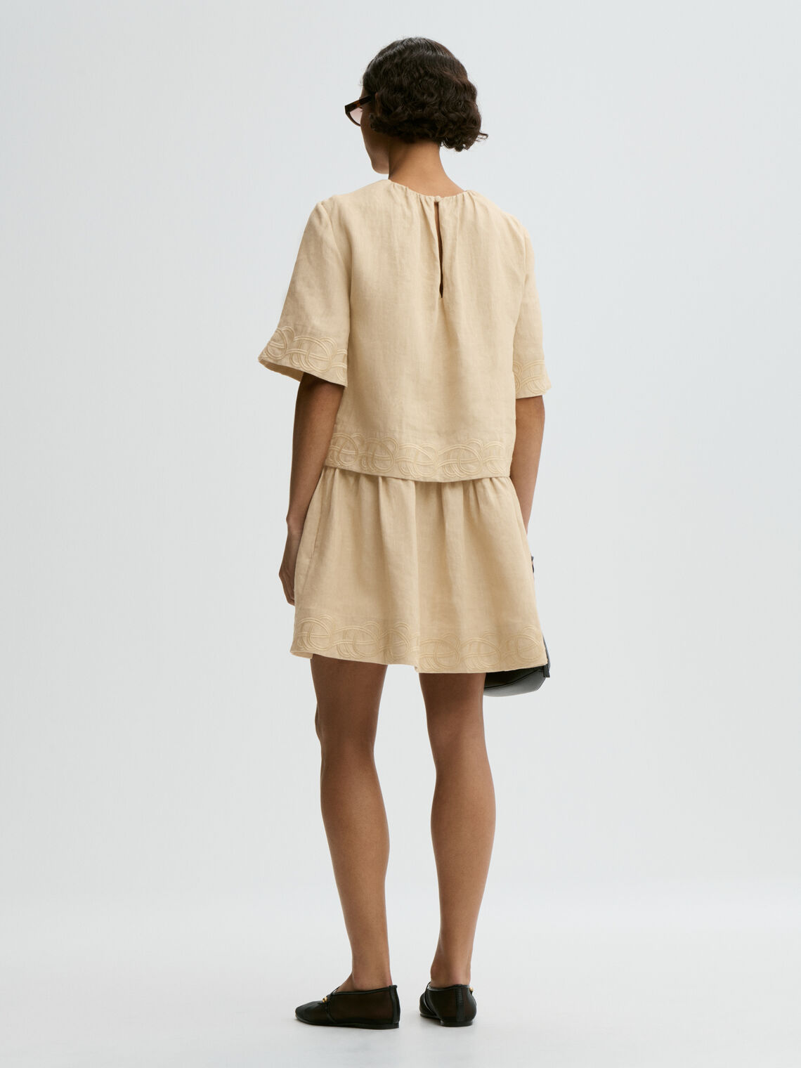 By Malene Birger Jania kjole i beige 100% lin med rund hals, knapplukking i nakken og swirl-broderi.