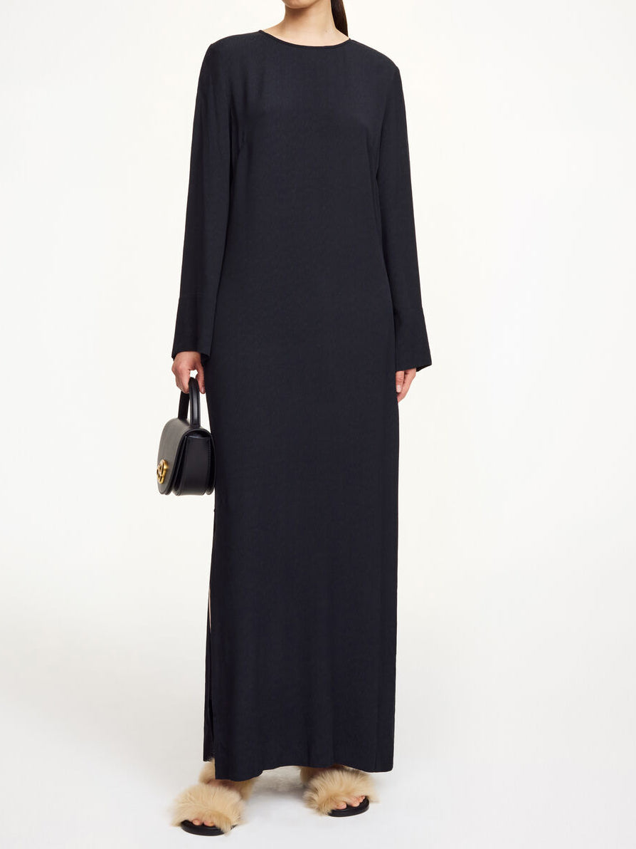 By Malene Birger Kallas lang kjole i sort viskose med rund hals, lange ermer, glidelås og splitt i siden.