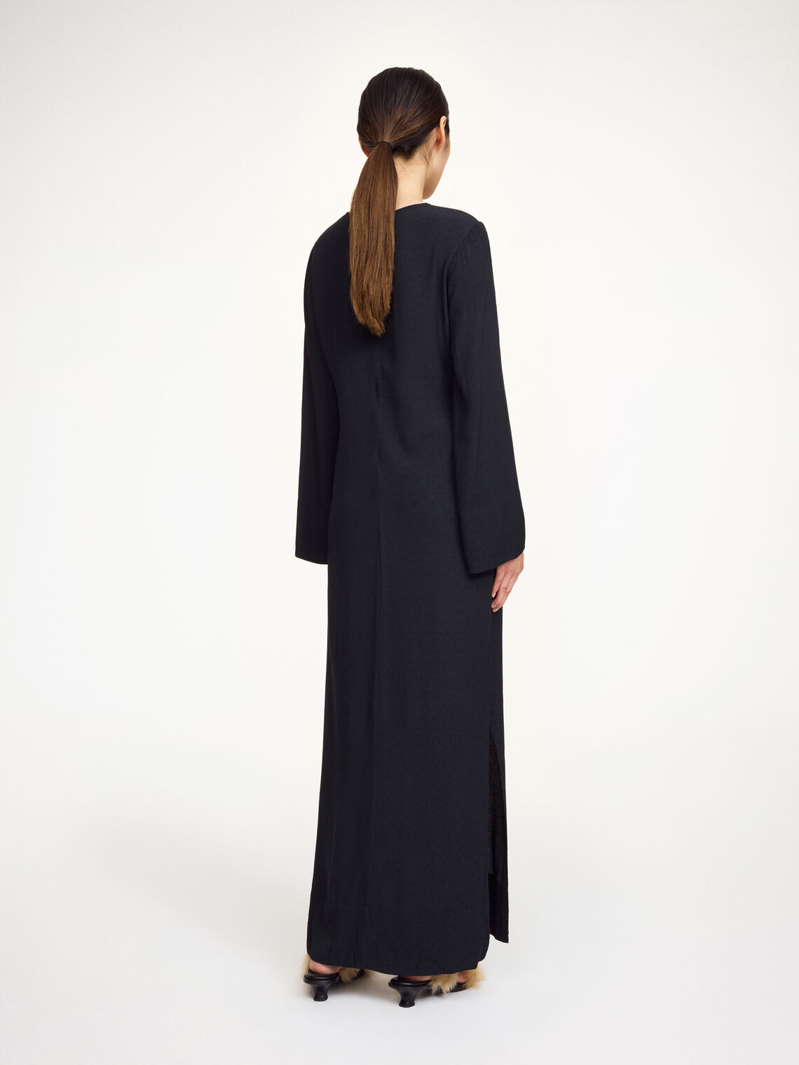 By Malene Birger Kallas lang kjole i sort viskose med rund hals, lange ermer, glidelås og splitt i siden.