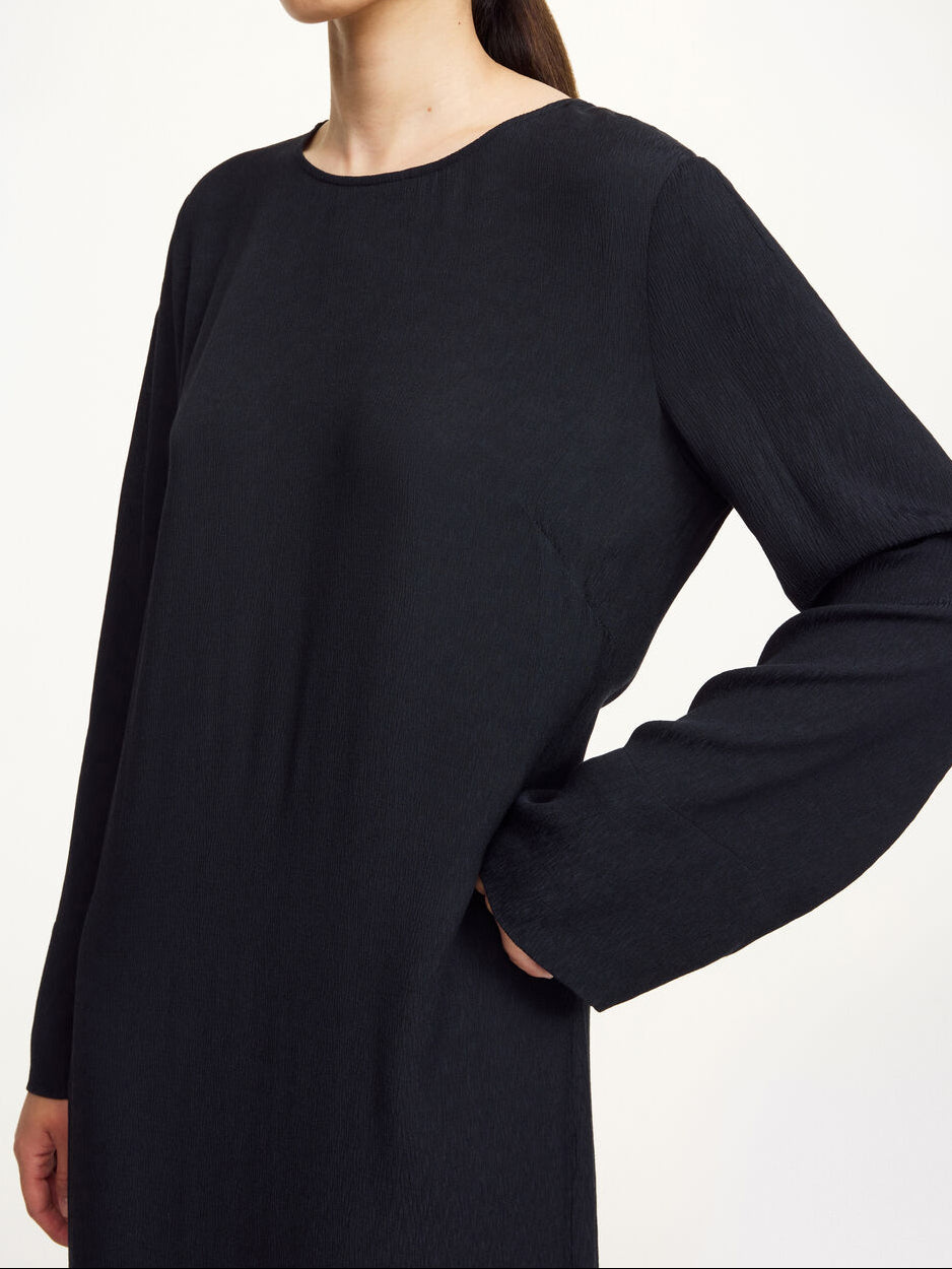 By Malene Birger Kallas lang kjole i sort viskose med rund hals, lange ermer, glidelås og splitt i siden.