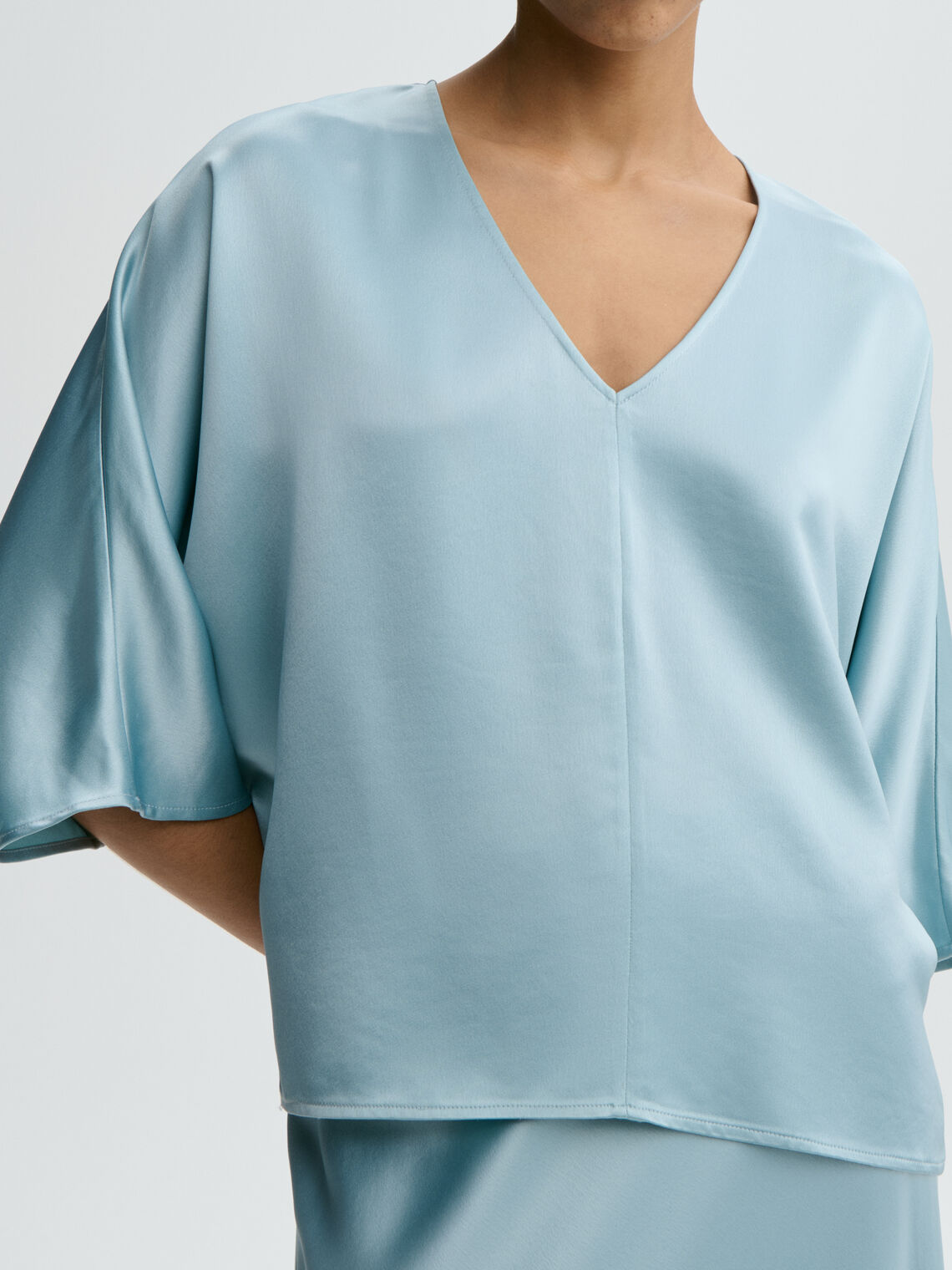 Lyseblå LUCIA satengbluse fra By Malene Birger, detaljbilde av acetat-stoff og splitt i siden.