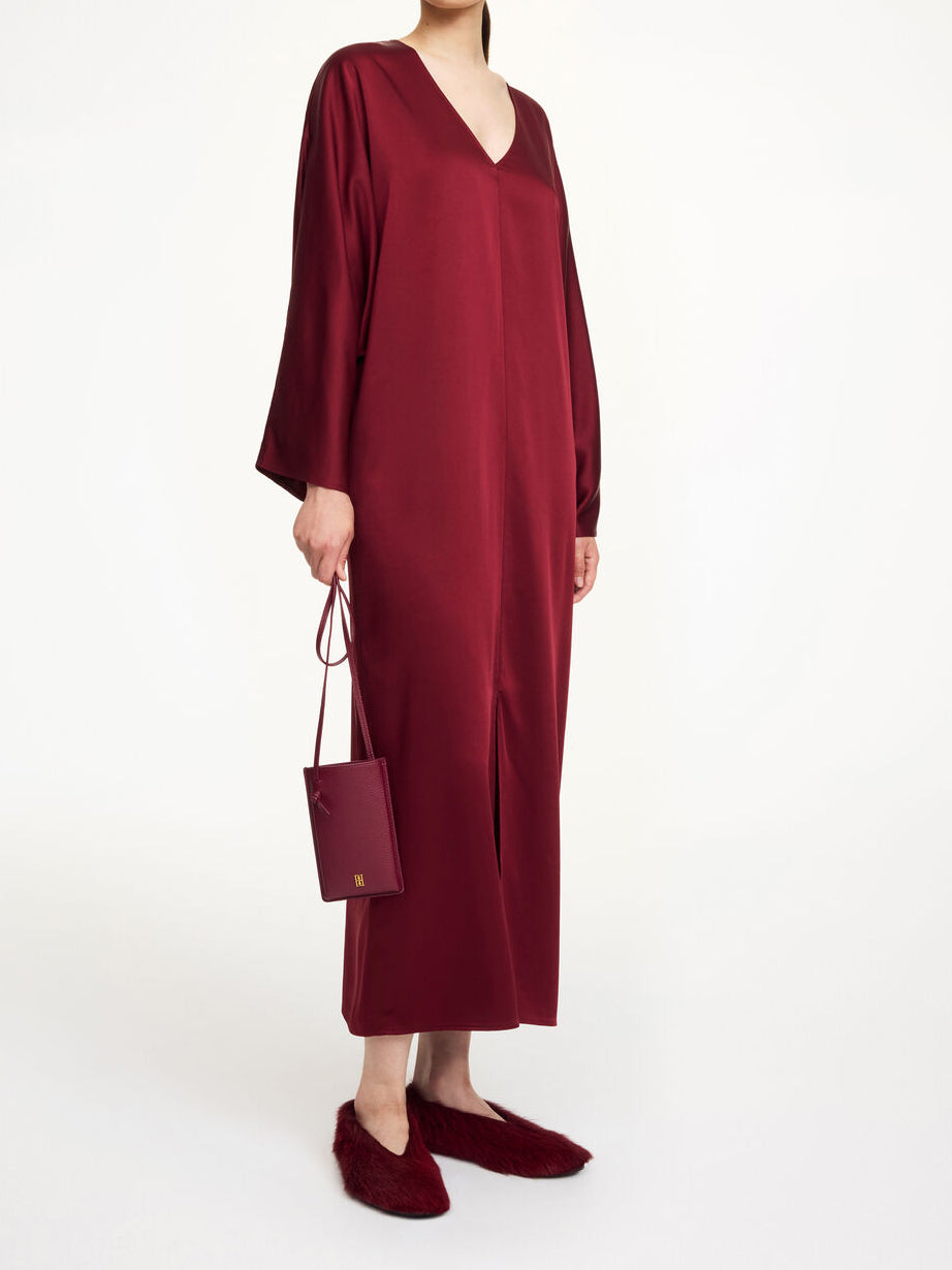 By Malene Birger Lucina ankel-lang satengkjole i burgunder acetat og polyester med v-hals, dolman-ermer og splitt i front.