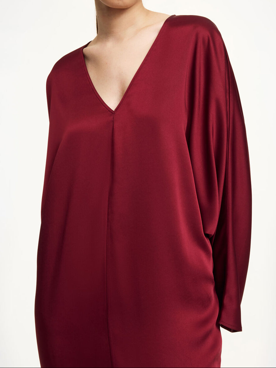 By Malene Birger Lucina ankel-lang satengkjole i burgunder acetat og polyester med v-hals, dolman-ermer og splitt i front.