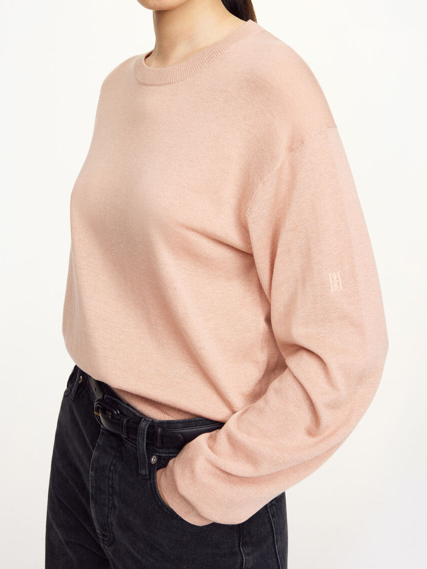 Delikat og tynn Mantea genser i fargen rosa fra By Malene Birger, laget i en miks av lyocell, ull og silke. Genseren har en fin rund hals, lange ermer med nette avslutninger og et lite monogram-broderi på armen.