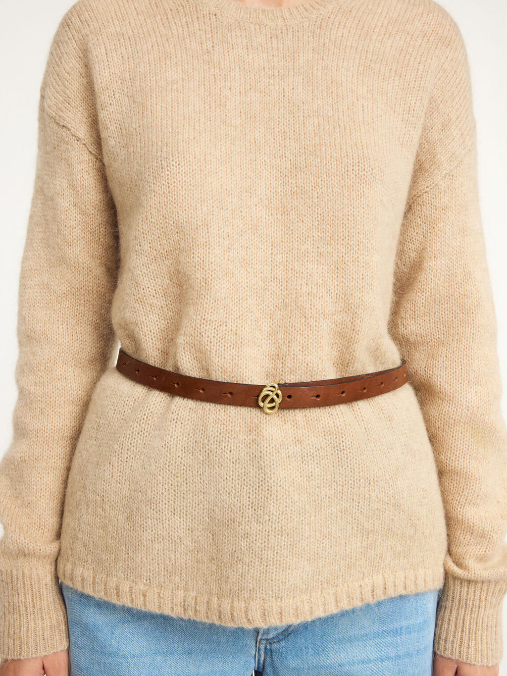 OUMA belte i brunt kuskinn med swirl-emblem spenne i gullfarge, detaljbilde av spenne.