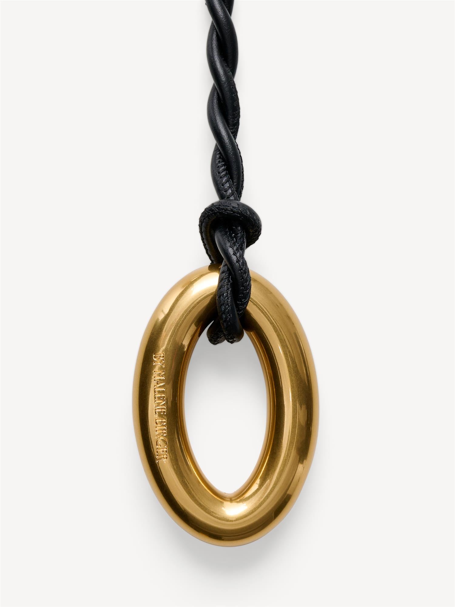 OVA SMALL knytte belte i sort kuskinn, detaljbilde av oval logo-spenne.