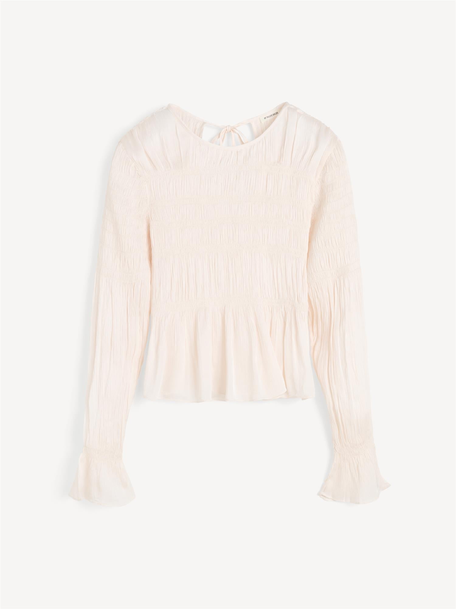 Hvit OVAS bluse fra By Malene Birger i 100% viskose med strukturstoff, dyp v-utringning bak, knyting i nakken og peplumkant.