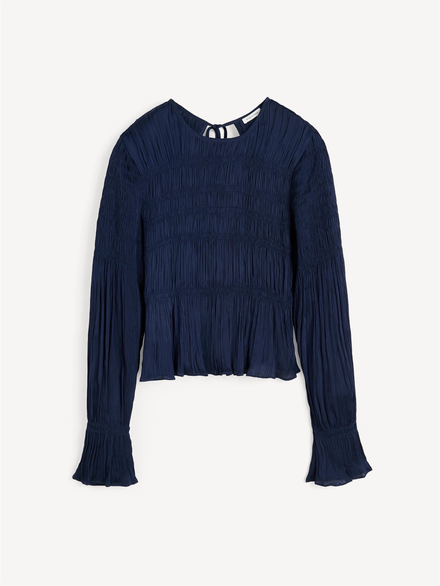 Mørkeblå OVAS bluse fra By Malene Birger i 100% viskose med strukturstoff, dyp v-utringning bak, knyting i nakken og peplumkant.