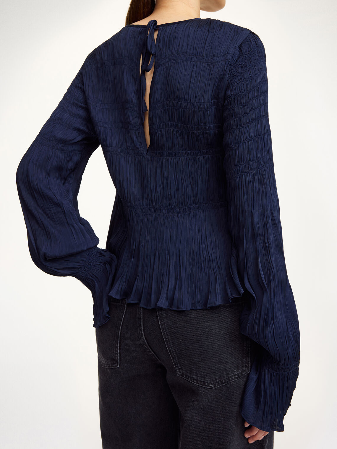 Detaljbilde av mørkeblå OVAS bluse fra By Malene Birger med strukturstoff og knyting i ryggen.