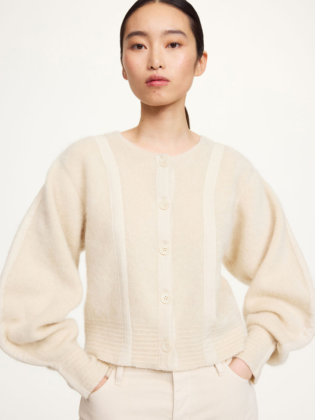 Nærbilde av kremfarget PERNILLE cardigan med knapper og bjelleermer i mohair-mix.