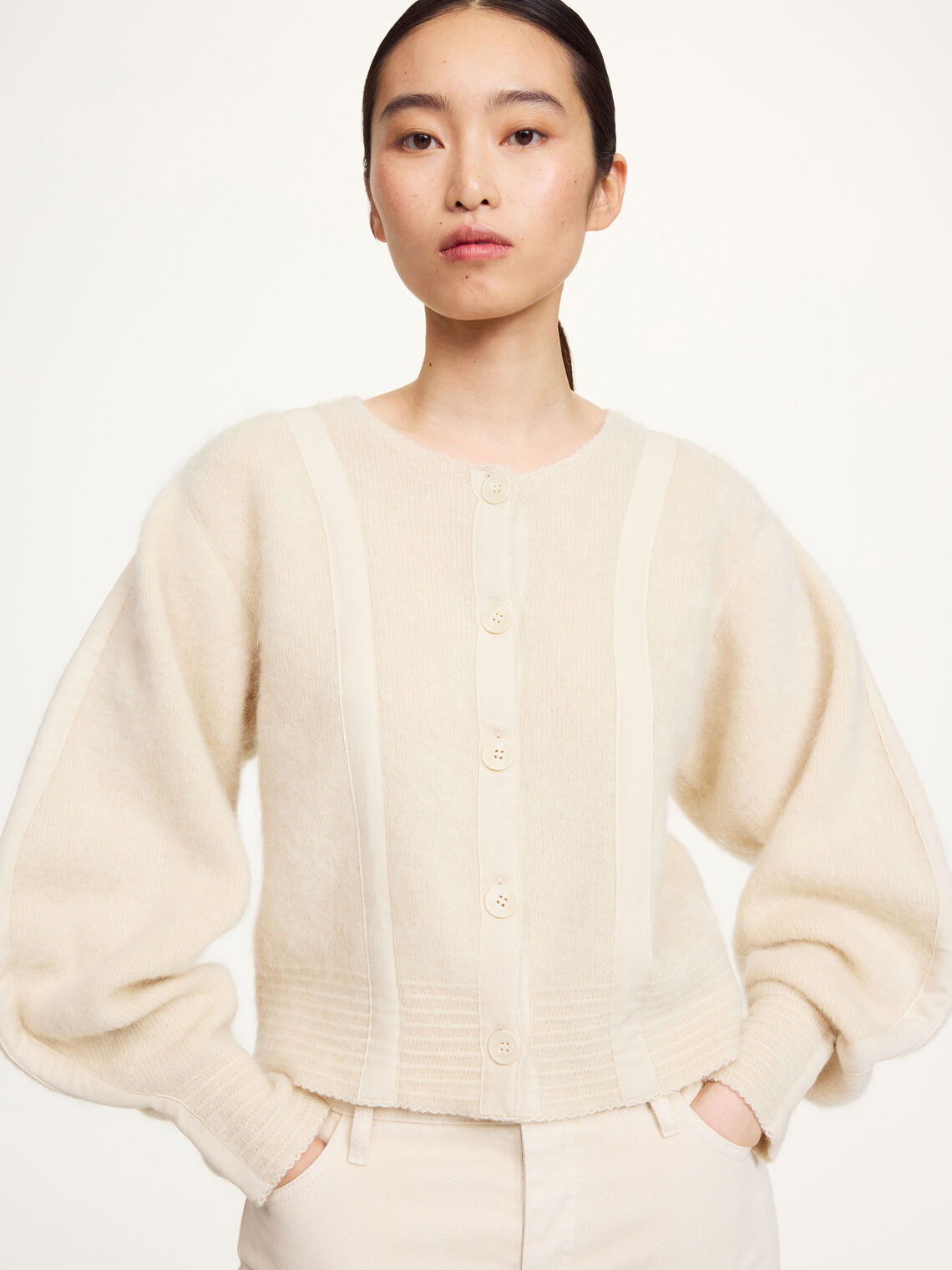 Nærbilde av kremfarget PERNILLE cardigan med knapper og bjelleermer i mohair-mix.