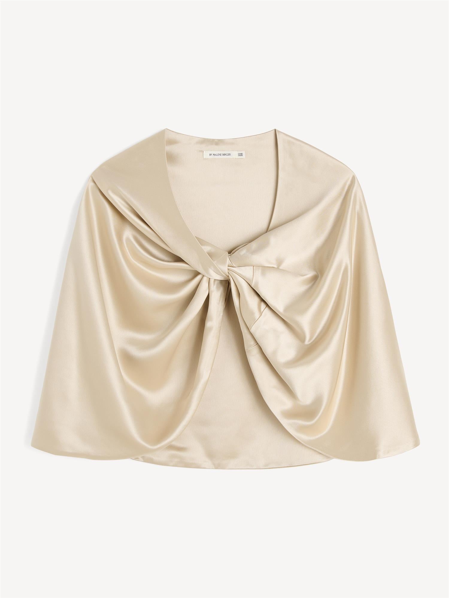 By Malene Birger PINLOS cape i kremfarget materiale med Signatur Flower-print. Rund halsringning og lange fallende linjer.