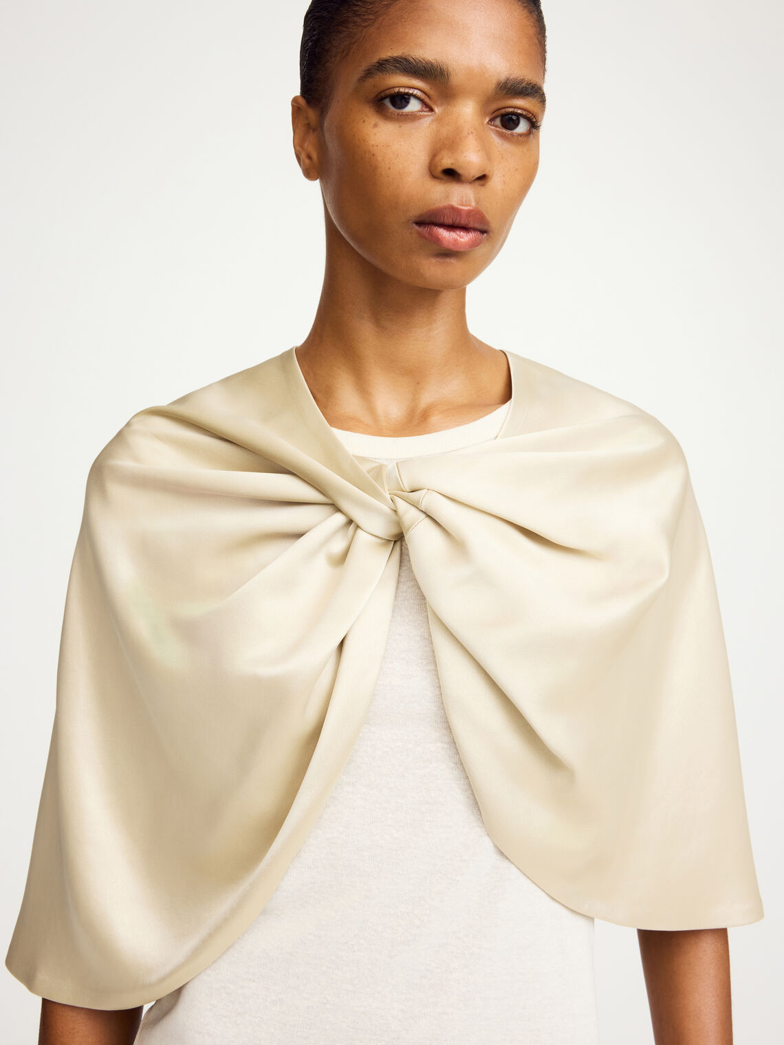 By Malene Birger PINLOS cape i kremfarget materiale med Signatur Flower-print. Rund halsringning og lange fallende linjer.