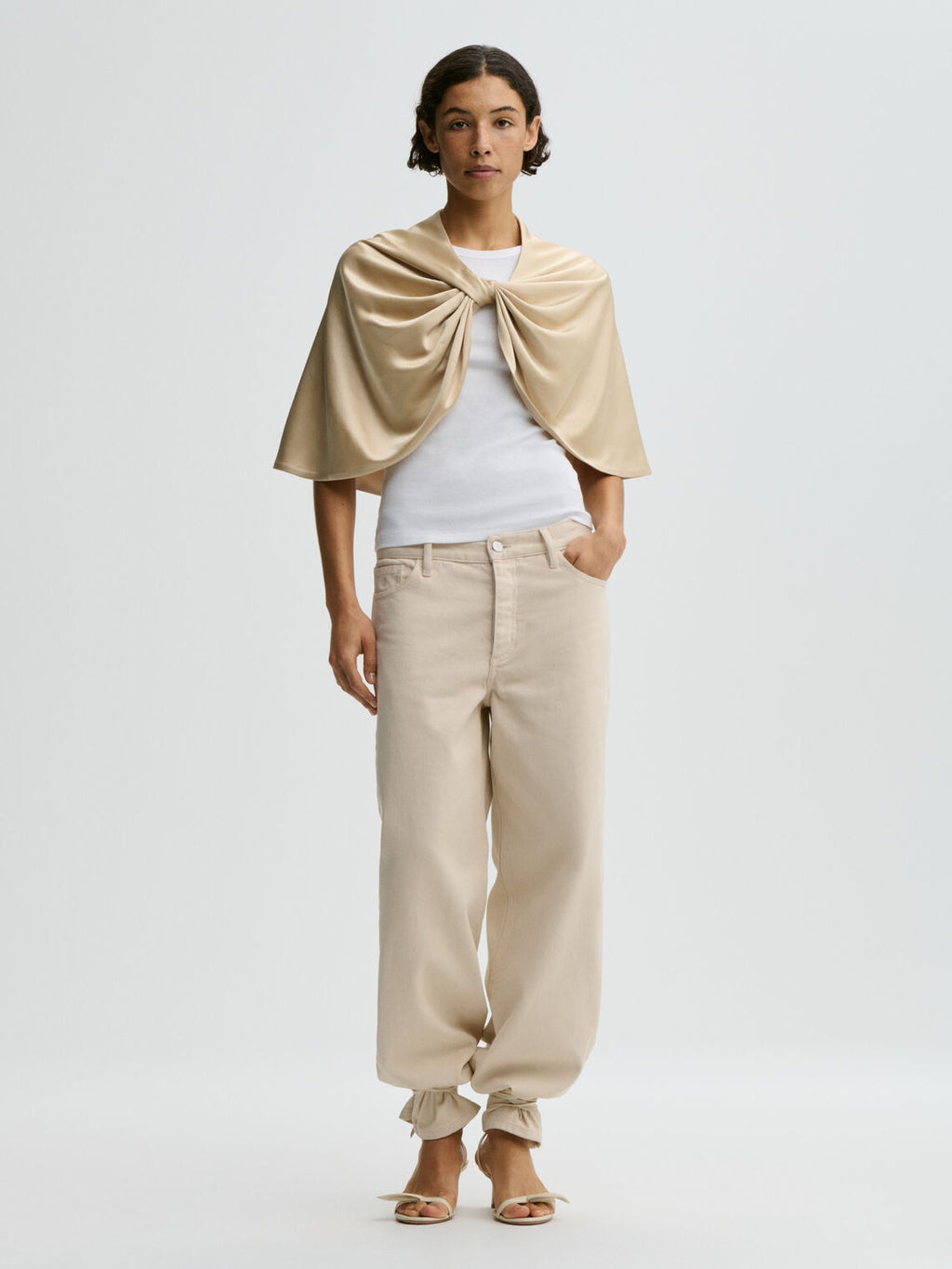 By Malene Birger PINLOS cape i kremfarget materiale med Signatur Flower-print. Rund halsringning og lange elegante fallende linjer.