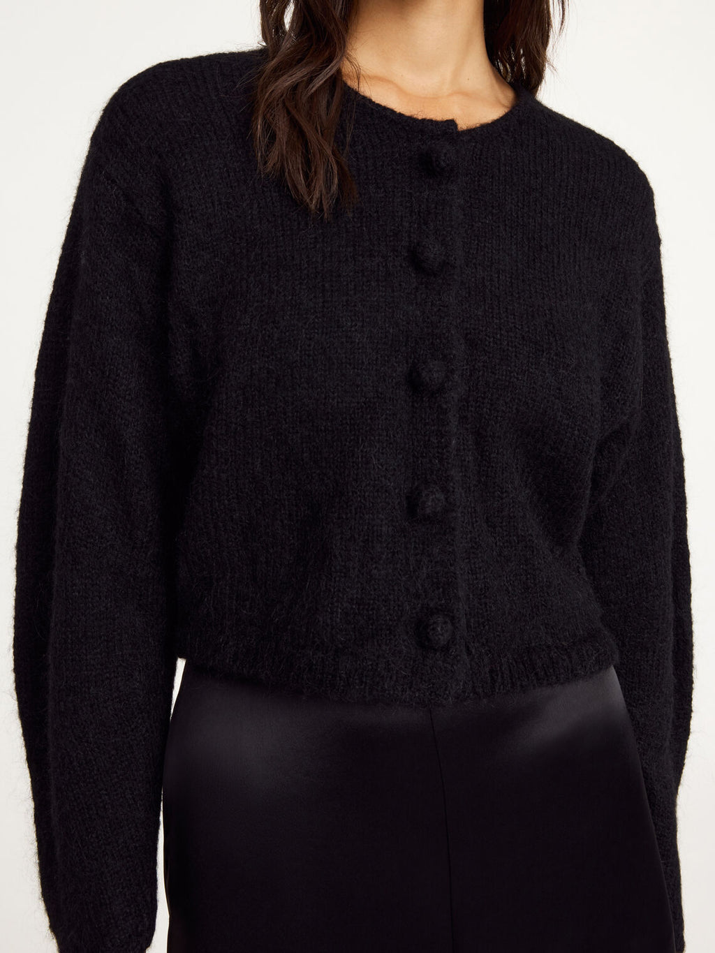 Nærbilde av sort ZHAREA cardigan med trukne knapper og buede ermer i ull og mohair.