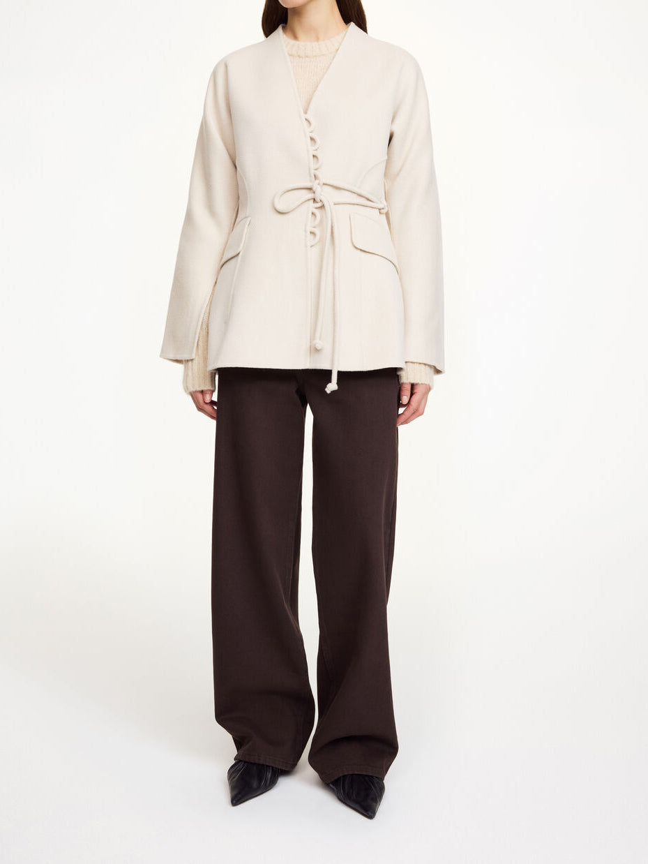 Lalou ulljakke i fargen hvit fra By Malene Birger laget i hundre prosent RWS-sertifisert ull. Jakken er en feminin variant av den klassiske blazeren med et elegant omslag som kan knytes på flere måter. Den har splitter på ermene, praktiske lommer i front og en justerbar lukking som gir et tidløst og moderne uttrykk.