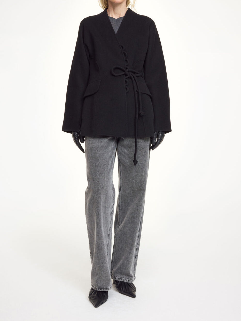 Lalou ulljakke i fargen sort fra By Malene Birger laget i hundre prosent RWS-sertifisert ull. Jakken er en feminin variant av den klassiske blazeren med et elegant omslag som kan knytes på flere måter. Den har splitter på ermene, praktiske lommer i front og en justerbar lukking som gir et tidløst og moderne uttrykk.