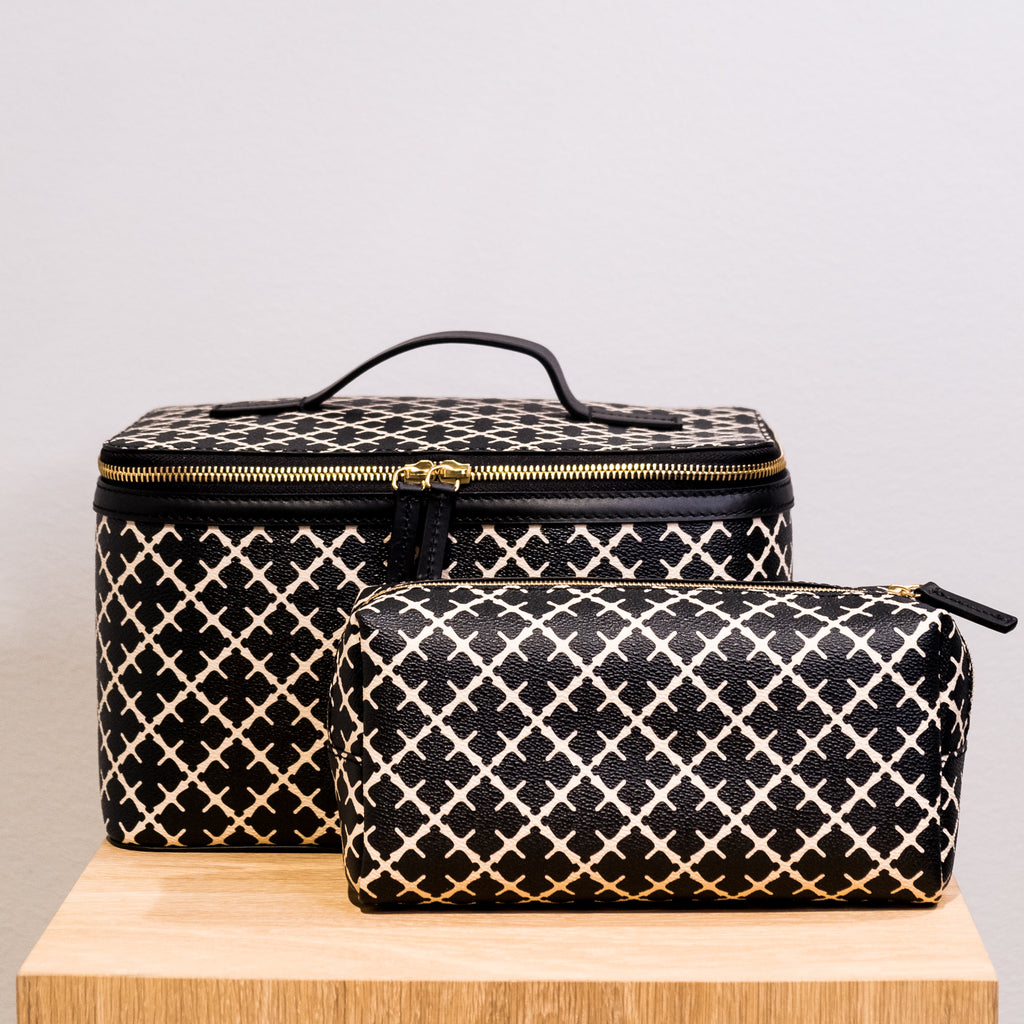 By Malene Birger Bae Beauty Box toalettmappe i sort, laget av polyvinylklorid med Signature Flower-print, med flere rom og en ekstra sminkepung.